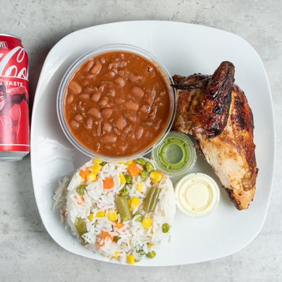 Grilled chicken, rice with vegetables, beans, and a Coca-Cola can on a white plate.